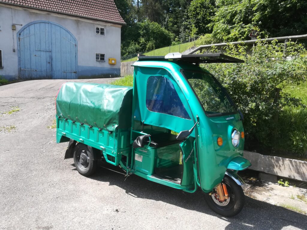 Grünes Cargo Runner E-Lastenrad mit Dach und Plane auf der Ladefläche