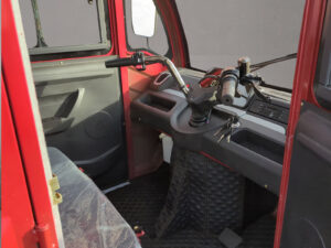 Innenraumansicht mit Lenkrad, Schalthebel und Fahrerbereich im roten Doppelkabiner